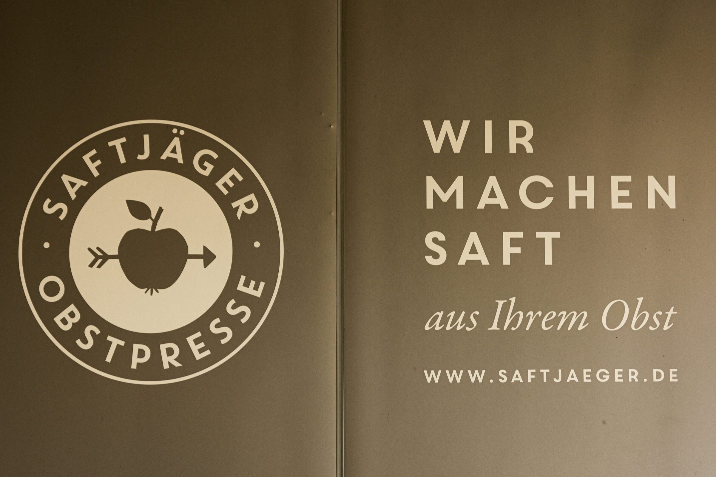 Die Aufschrift „Saftjäger Obstpresse – Wir machen Saft aus Ihrem Obst“ an der Wand des Presshauses